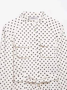 Detailed close-up of white polka dot shirt collar with flap pockets and waist tie