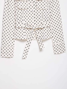 Close-up of polka dot shirt featuring front pockets and elegant waist tie detailing