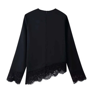 Detail of black satin blouse featuring delicate lace trim on cuffs and asymmetric hemline