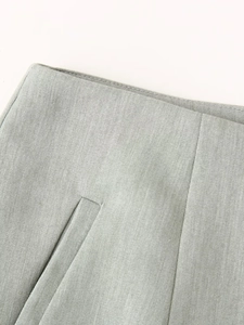Detail of the waist design and welt pocket on light grey-green fabric shorts