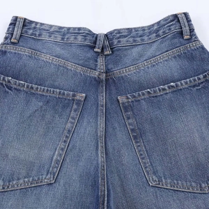 Detailed view of the back pockets and orange contrast stitching on blue denim jeans