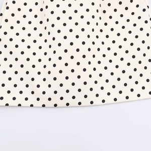 Close-up detail of vintage polka dot fabric showing black dots on creamy white material