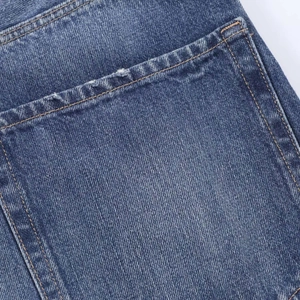 Detail of blue denim fabric showing contrast stitching and ripped distressed texture