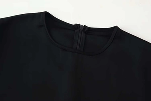 Detail shot of black round neckline with refined hidden zipper and high-quality fabric texture