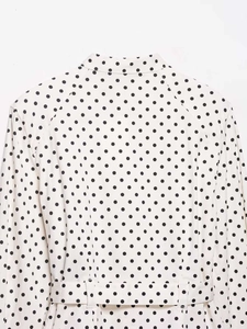 Detail of white polka dot jacket with stand collar and matching waist belt