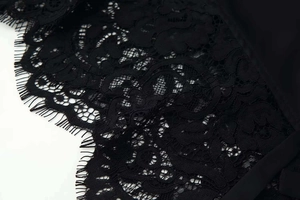 Detailed macro view of delicate black eyelash lace fabric with floral embroidery patterns