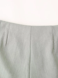 Detail view of high-waist pleated shorts in light grey fabric with clean stitching