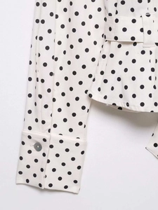 Detailed close-up of polka dot shirt cuff with translucent buttons and waist belt loop