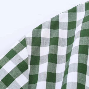 Detailed close-up showing sewing craft and texture of green plaid cotton dress fabric