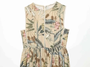 Detail of tropical plant print and white hollow lace trim on a beige sleeveless dress