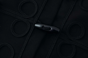 Detail of elegant black jacket featuring intricate braided cord knots and horn toggle button
