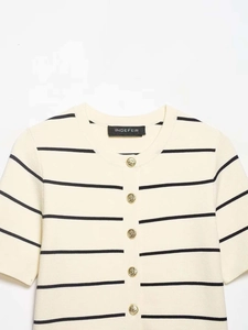 Close-up of cream knit cardigan with black stripes and embossed gold buttons
