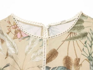 Detail of floral print dress featuring tropical leaves and white scalloped lace neckline