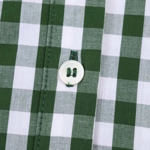 Detail of green gingham shirt dress featuring neat stitching and white resin button