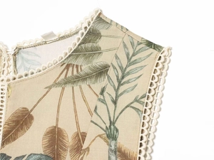 Detail of tropical leaf print dress with intricate white crochet lace on the neckline