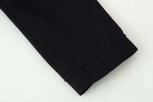 Detailed macro view of black ribbed knit fabric cuff with premium seamless stitching finish