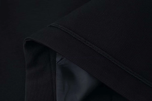 Close-up of black jacket with intricate braided trim and smooth satin lining