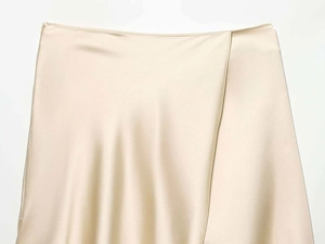 Detail of elegant champagne satin wrap skirt featuring smooth fabric and draped waistline