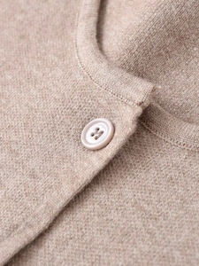 Close-up of the beige knitted cardigan featuring fine wool texture and matching button detail