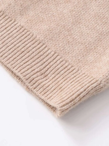 Detailed macro view of the soft beige knitted fabric texture and ribbed cuff finishing