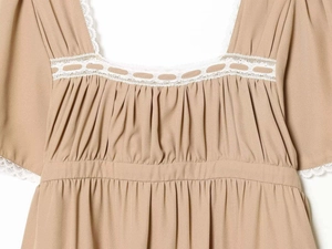 Détail d'une robe marron chameau avec bordure en dentelle blanche et col carré plissé