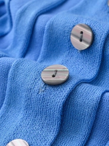 Macro detail of royal blue knit cardigan featuring marble textured button closure