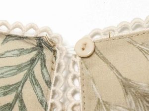 Detail of linen dress featuring botanical leaf print, crochet lace trim and resin button