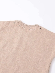 Detail of beige knit top featuring shoulder tie straps and silver metal eyelets