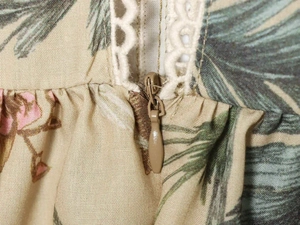 Detail of invisible brown zipper and cream lace trim on tropical floral print dress