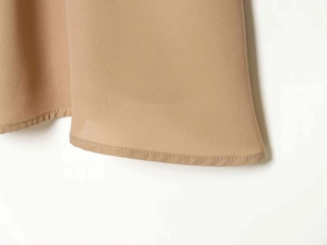 Gros plan détaillé montrant la double couture renforcée et la texture de l'ourlet brun clair