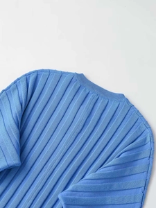 Detailed close-up of bright blue ribbed knit texture and crew neckline of the sweater