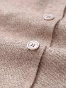 Close-up of neutral knit cardigan fabric texture and minimalist round button detail