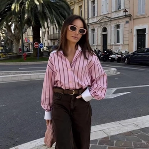 European style women's striped pink shirt with white contrast cuffs and brown trousers