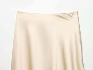 Detail of champagne satin skirt waist featuring a smooth texture and hidden side zipper