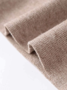 Close-up of light brown knitted fabric texture showing fine knit craftsmanship and soft fiber