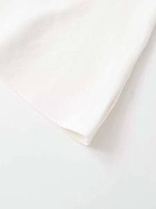Close-up of the delicate white knit fabric texture and high-quality cuff stitching details