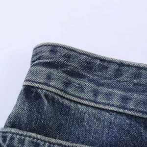 Dettaglio della vita di pantaloncini in denim con borchie e trama lavata scura