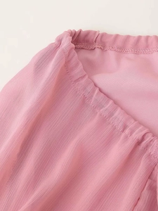 Dettaglio del tessuto in chiffon rosa con volant a strati e trama elastica in vita arricciata
