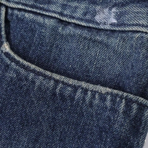 Primo piano del tessuto denim blu con cuciture dettagliate ed effetti invecchiati