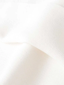 Macro shot of white knitted fabric texture showing small mesh structure and fiber details