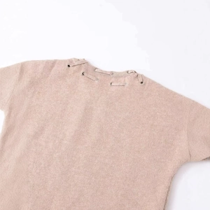 Minimalist knit sleeveless top featuring elegant shoulder tie straps and metal eyelet details