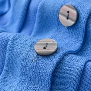Blue knitted cardigan featuring stylish accordion sleeves and marble pattern buttons
