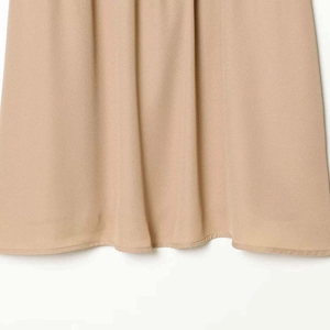 Gros plan d'une robe en dentelle beige montrant l'ourlet et la texture du tissu de qualité