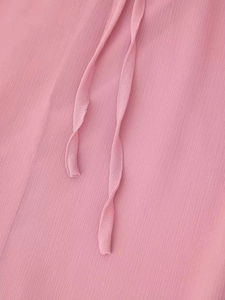 Dettaglio dell'abito in chiffon rosa che mostra la trama increspata e i lacci coordinati
