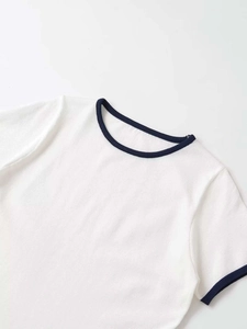 Close-up of white knit top featuring navy blue contrast ribbed neckline and texture