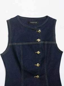 Detail view of dark blue denim vest featuring unique gold irregular metal buttons
