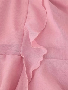 Dettaglio del tessuto in chiffon rosa a strati con bordi a balze e trama morbida