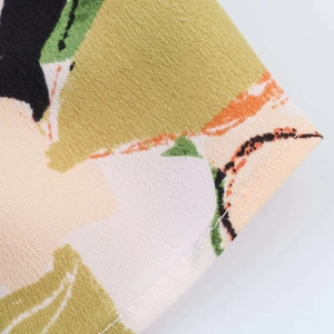 Dettaglio ravvicinato della camicetta in chiffon floreale con cuciture e stampe astratte