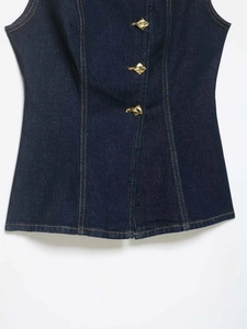Detail of dark blue denim vest featuring unique gold buttons and contrast yellow stitching