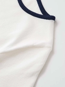Close-up of contrast trim collar on a cream knit top with navy blue ribbed edges